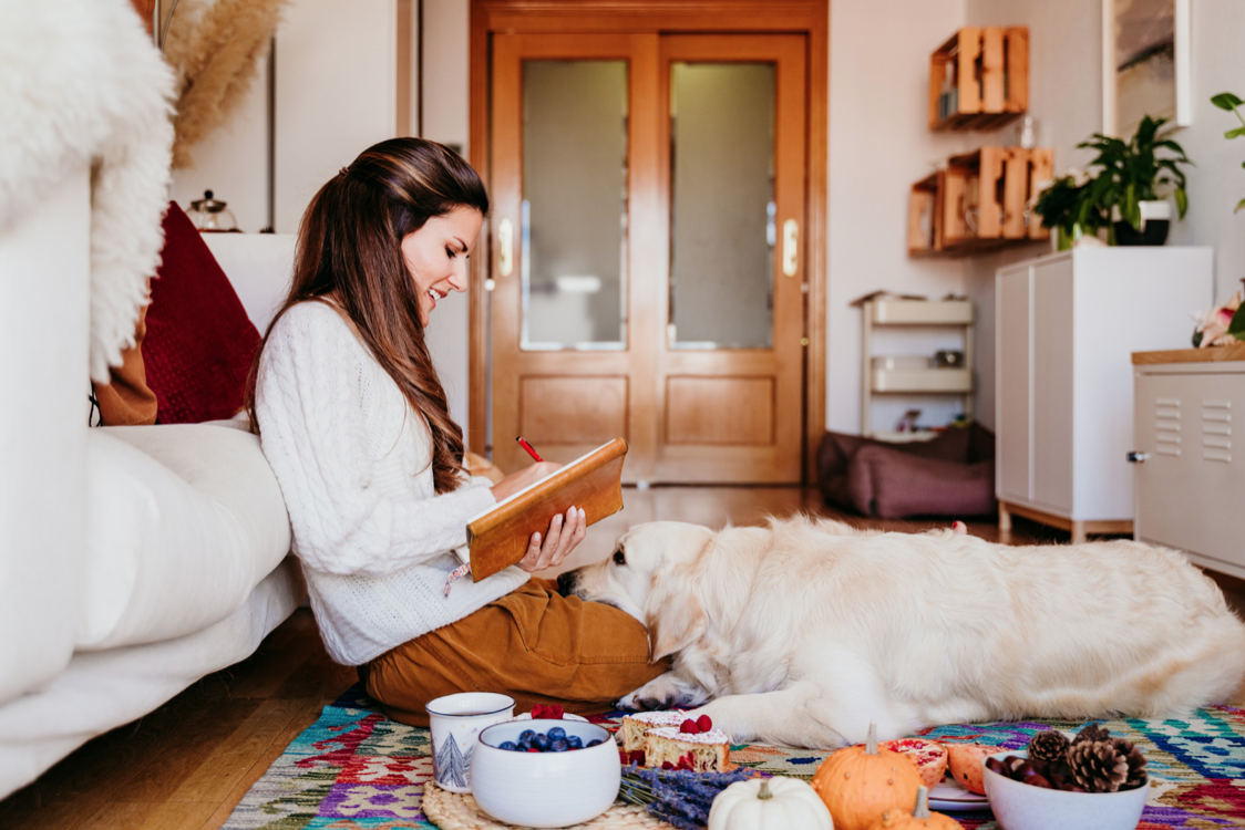 woman writing in notebook with her dog next to her